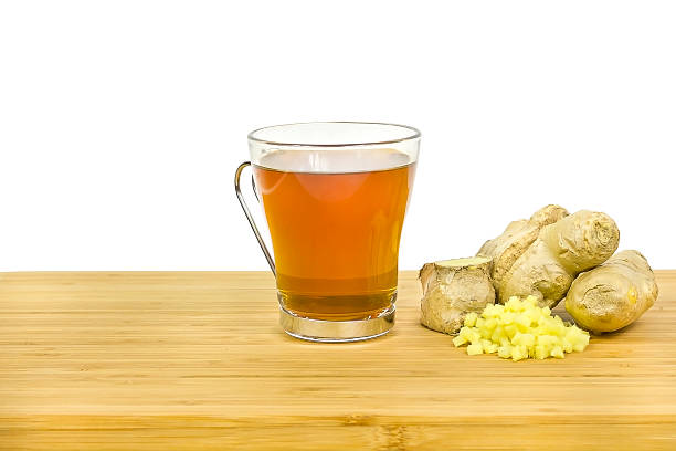 Bright amber herbal tea in a glass mug with ginger slice